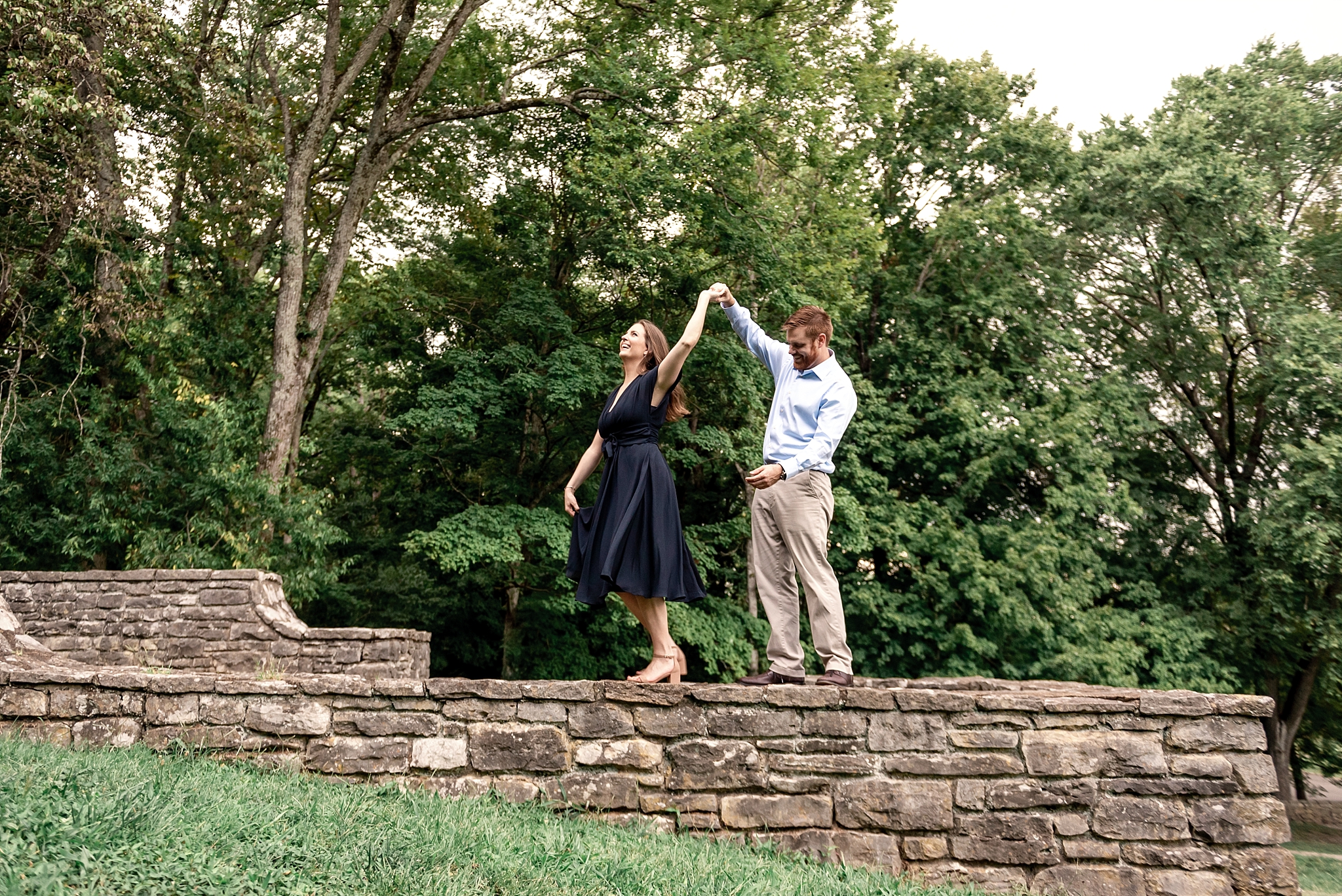 Engaged couple dancing on stone wall