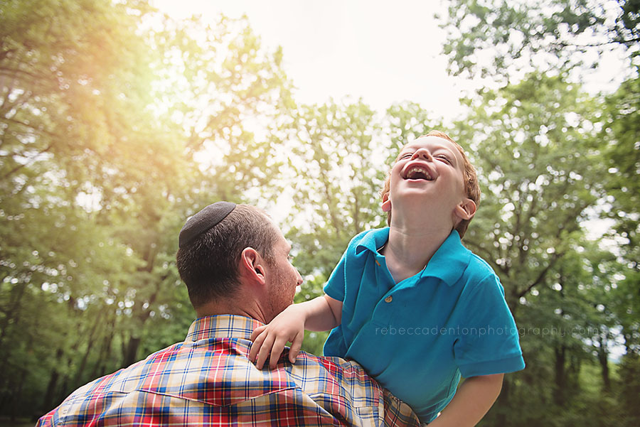 Child laughs while playing with father during a family photo session in Nashville