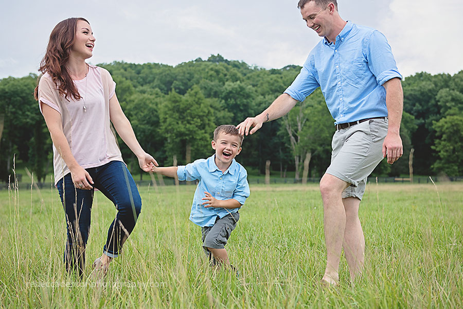 Family of three plays together in a field during a photo session in Nashville, TN