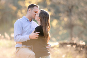 Engaged couple kissing in woods